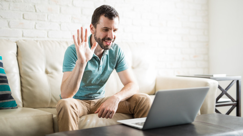 man waving to laptop 